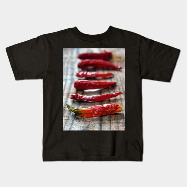 Dried chili peppers on a wooden board Kids T-Shirt by naturalis